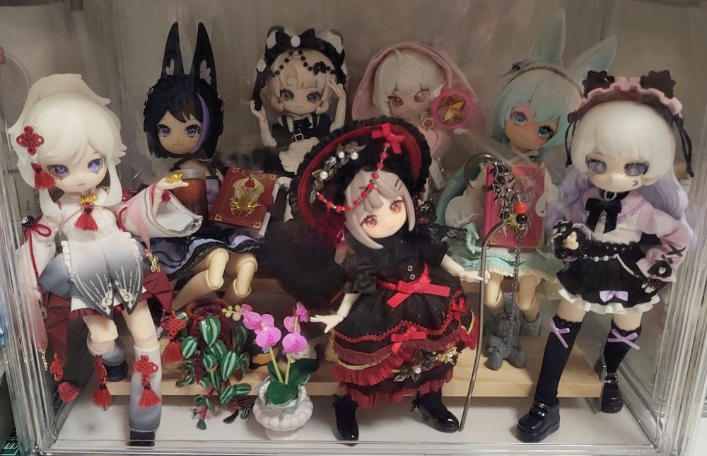 closeup of the bottom display case in the taller dolltower, featuring another hairpin stick staff, miniverse make it mini diy plants, and items from a cardcaptor sakura gacha set