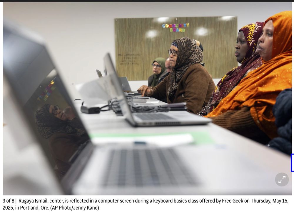 4 hijabi women sitting with laptops open in front of them and very serious expressions. (one man is slightly visible) 3 of 8 | Rugaya Ismail, center, is reflected in a computer screen during a keyboard basics class offered by Free Geek on Thursday, May 15, 2025, in Portland, Ore. (AP Photo/Jenny Kane)