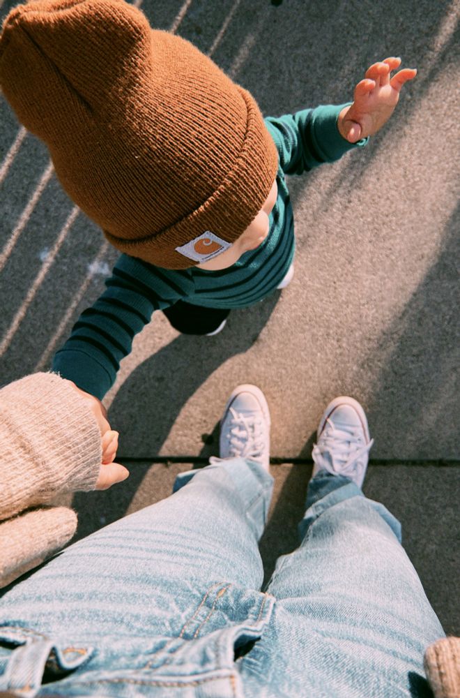 Picture taken from above of white Converse shoes and holding a baby’s hand