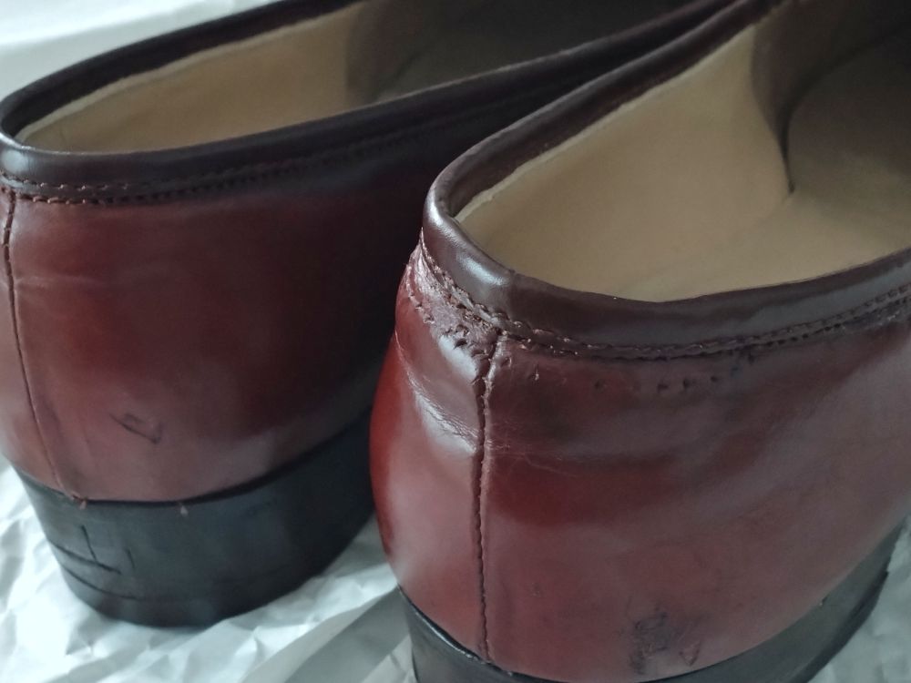 The heel sides of the same shoes; very thin strips of leather have been newly sewn onto the rims. One shoe has some small needle holes made from previous repair