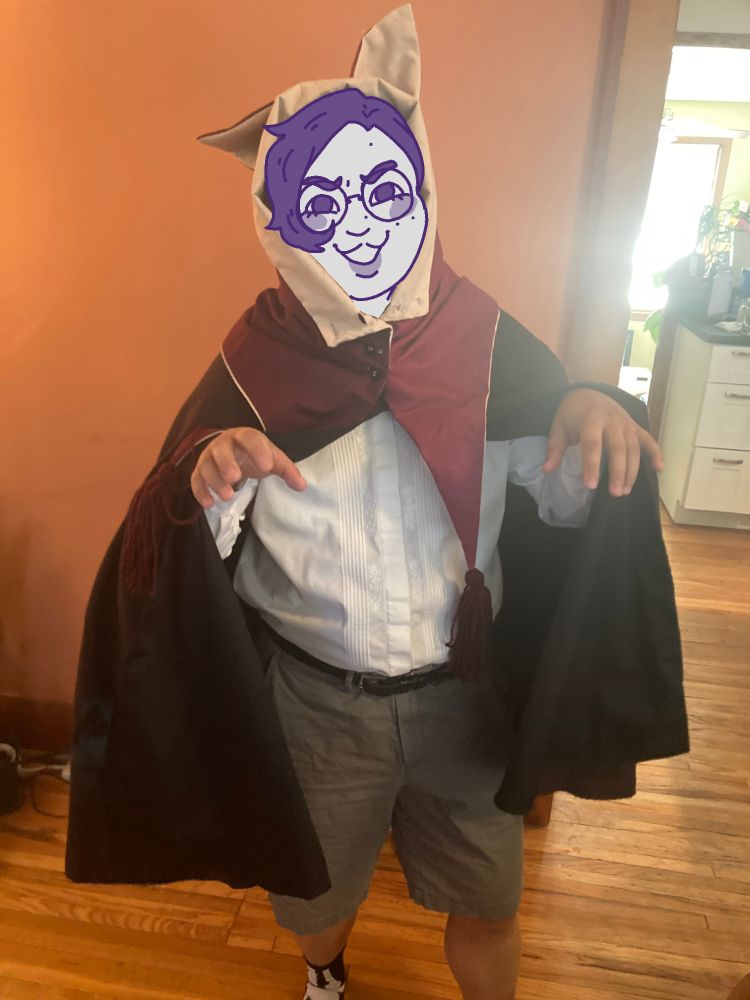 a photo of me wearing the cloak and cat hood, but with my arms raised like im pretending to have my claws out. my face is still drawn over.