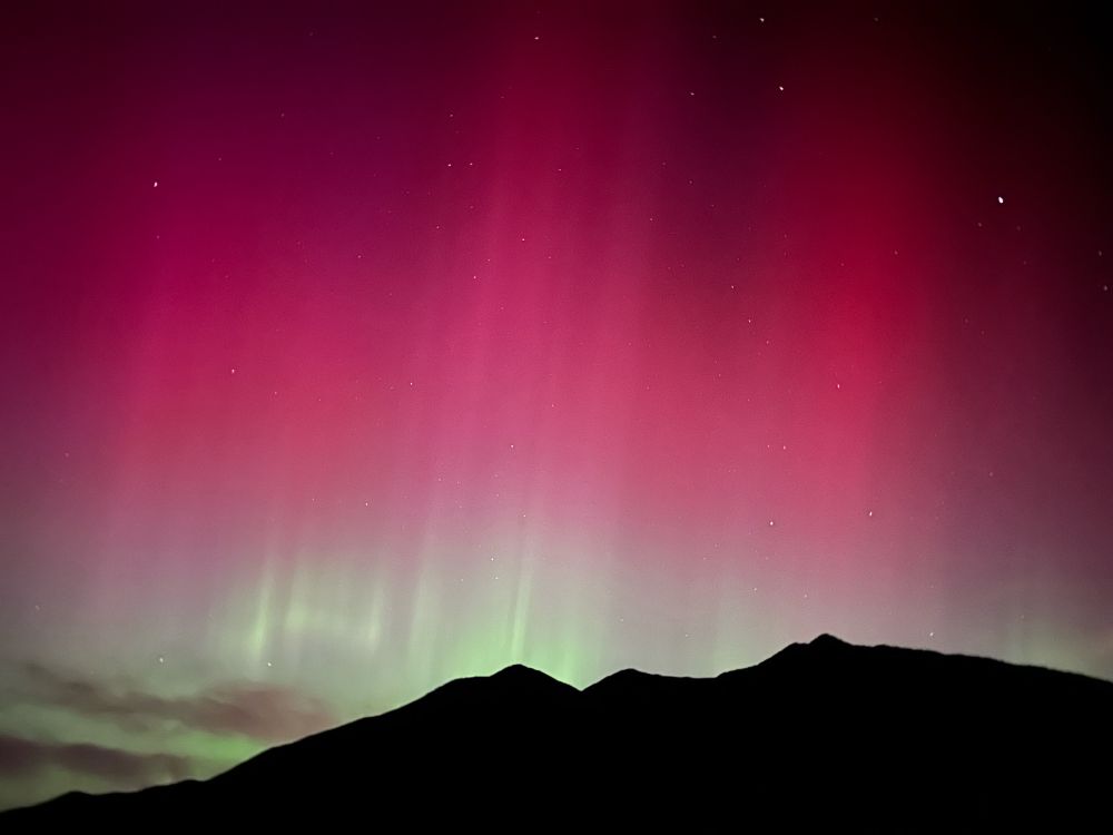 A rich pink and light green series of pillars sit on the horizon, with the green slowly transitioning to a pink as altitude rises