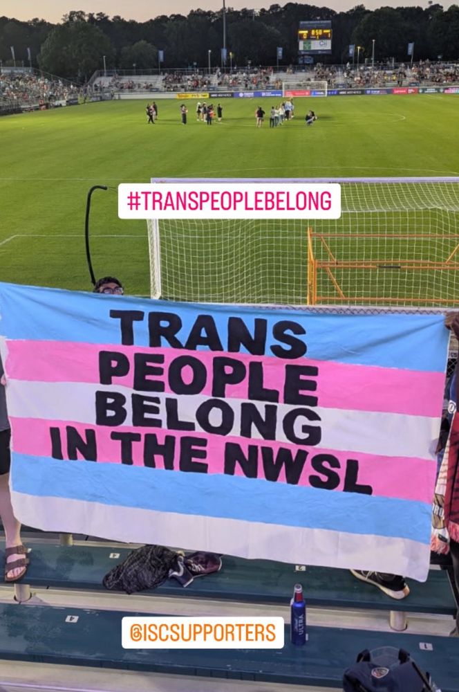 Uproar NC trans flag banner that reads trans people belong in the NWSL 