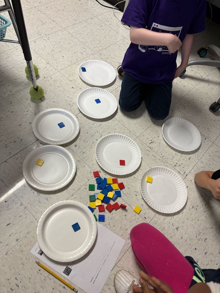 3 students with 8 paper plates and a pile of tiles. There is 1 tile on each plate. 