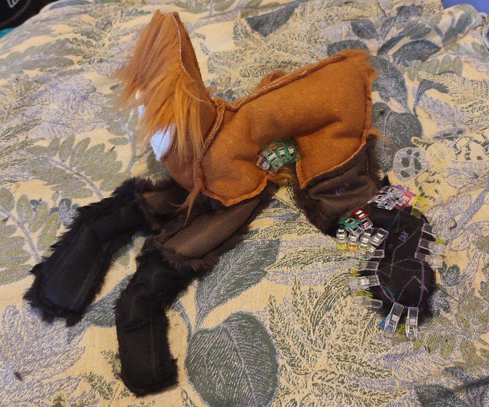 A work in progress plush. It is a quadrupedal, rusty coloured animal with long dark legs and a white throat patch.