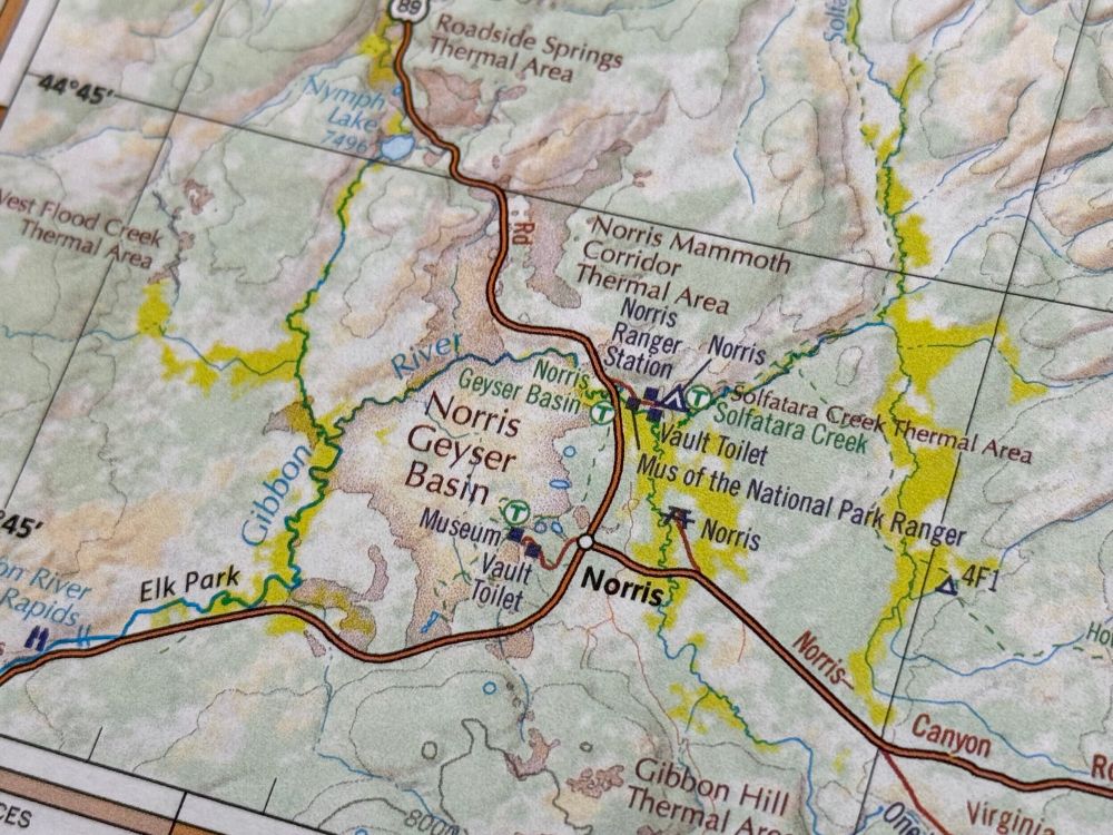 Closeup of the Norris area in Yellowstone, with red type and a red tint showing thermal areas on the landscape.