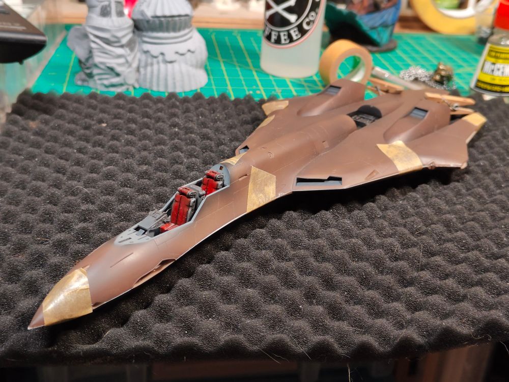 Anime themed aircraft fuselage primed brown and taped securely together while the cement cures.