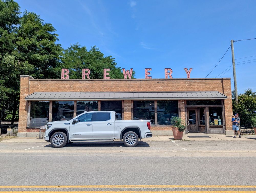 Photo looking across a street at a low slung brick commercial building with the word brewery in letters standing on top of the parapet wall.