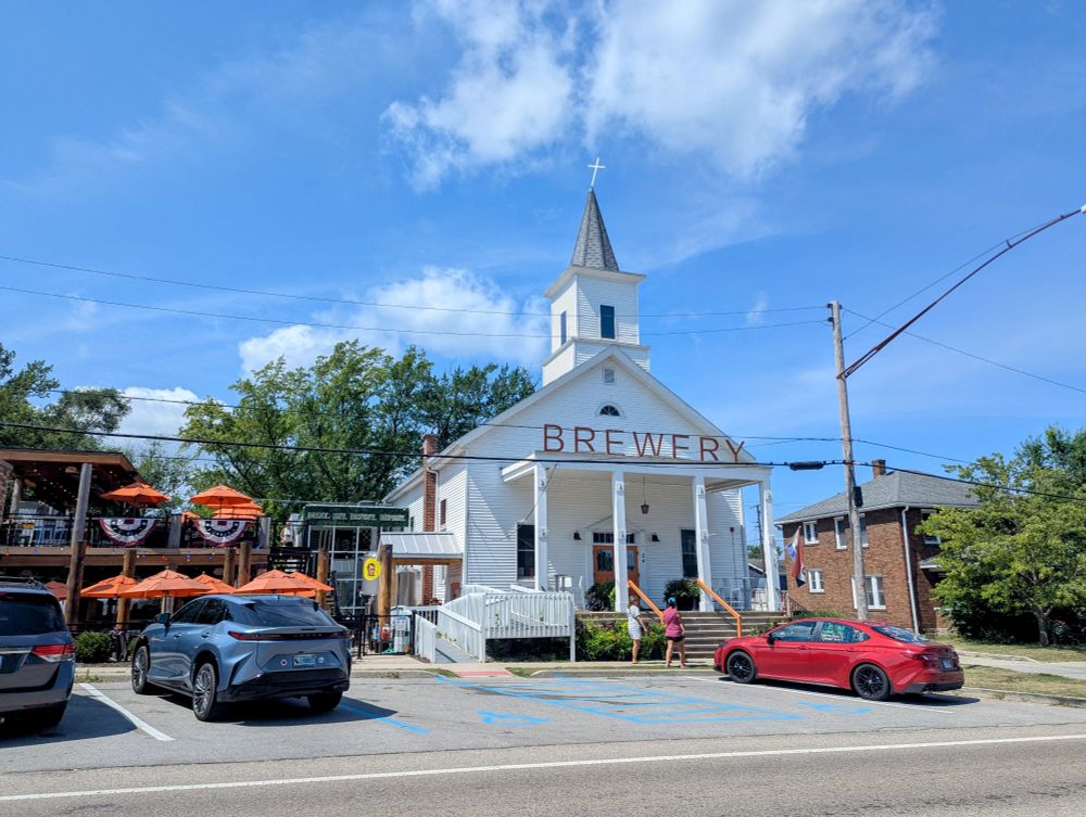 Photo looking across a street at a former traditional looking white church that has the word brewery across the front in very large letters. This is in New Buffalo and I did not stop.