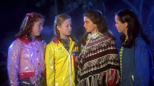 A scene from film Now and Then featuring, from left, Chrissie, Tini, Sam, and Roberta. Sam is wearing a crochet poncho in shades of purple and brown or burgundy.