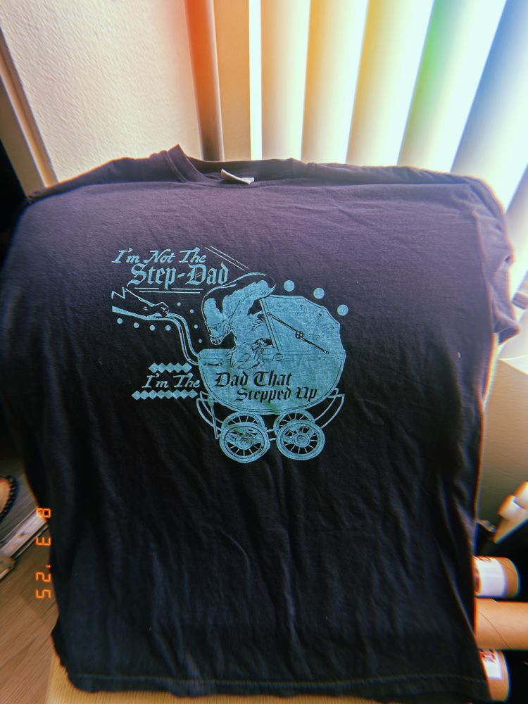 A shirt featuring a xenomorph in a stroller that reads “I’m not the step-dad, I’m the dad that stepped up”