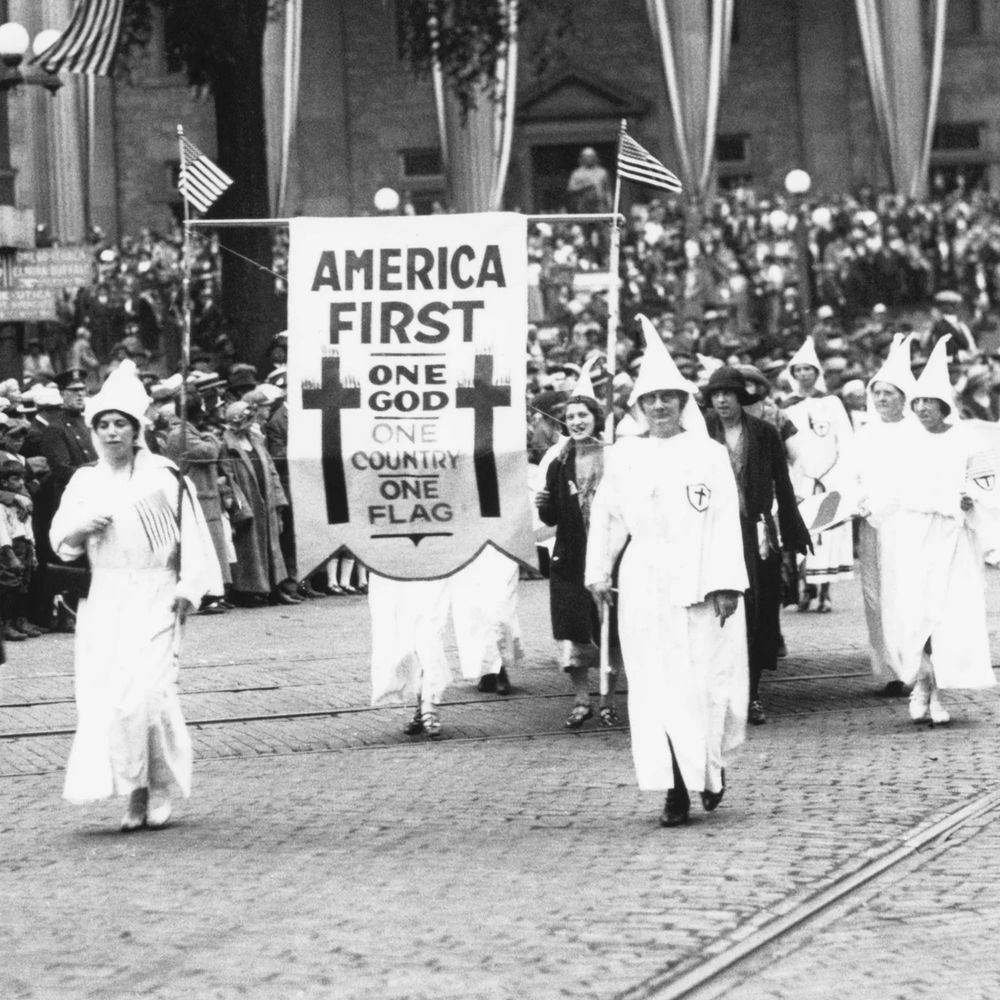 Pic of the kkk marching with an “America first” sign

