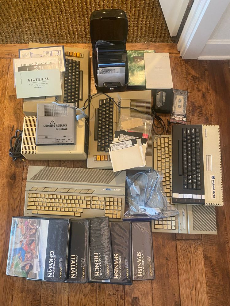 A pile of three Atari eight but computers, two Atari STs and various old software displayed on the floor