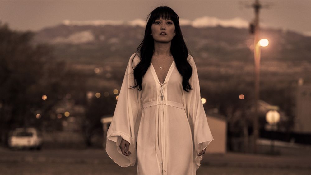 Hana Mae Lee plays Scottie, she is alone walking down a suburban street in a beautiful white gown