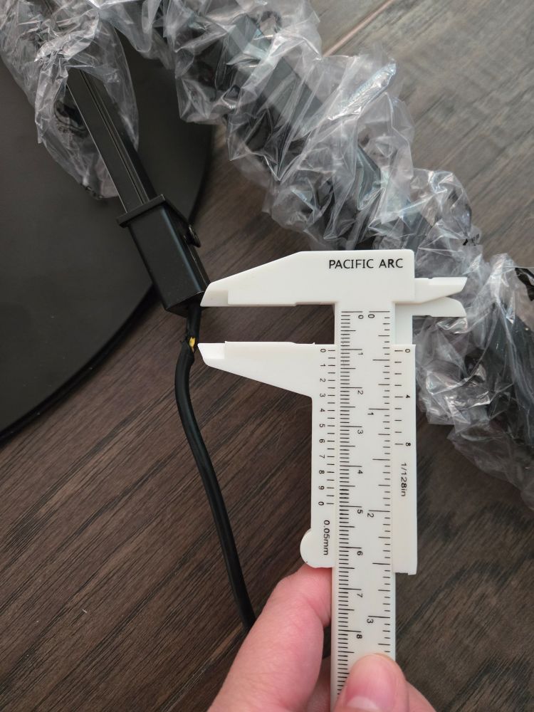 Photo of white calipers measuring the length of undamaged black eletrical wire before its damaged section exposing yellow wire. The undamaged section measures 3/8th of an inch.
