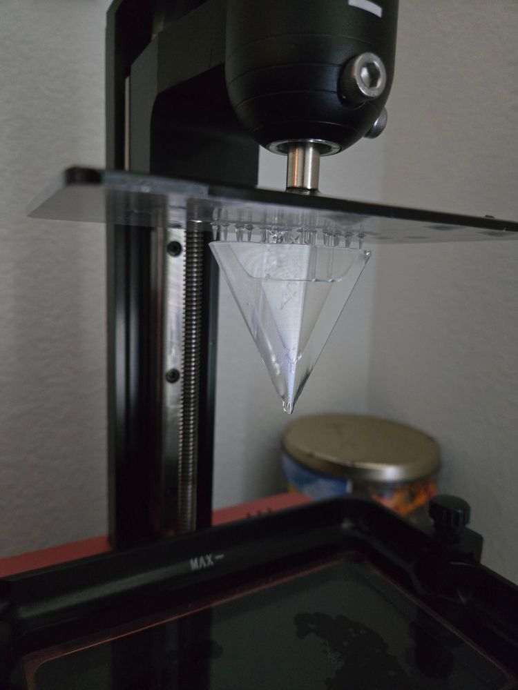 Clear triangulae resin piece upside down on the printer build plate.