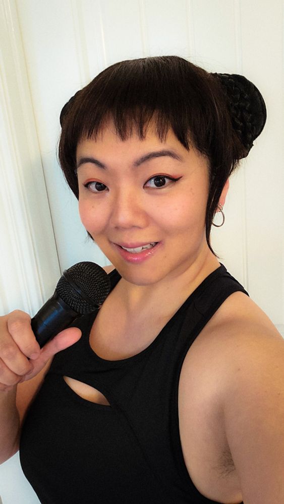 Photo of JWo cosplaying as Zoey from the movie K-Pop Demon Hunters holding a microphone