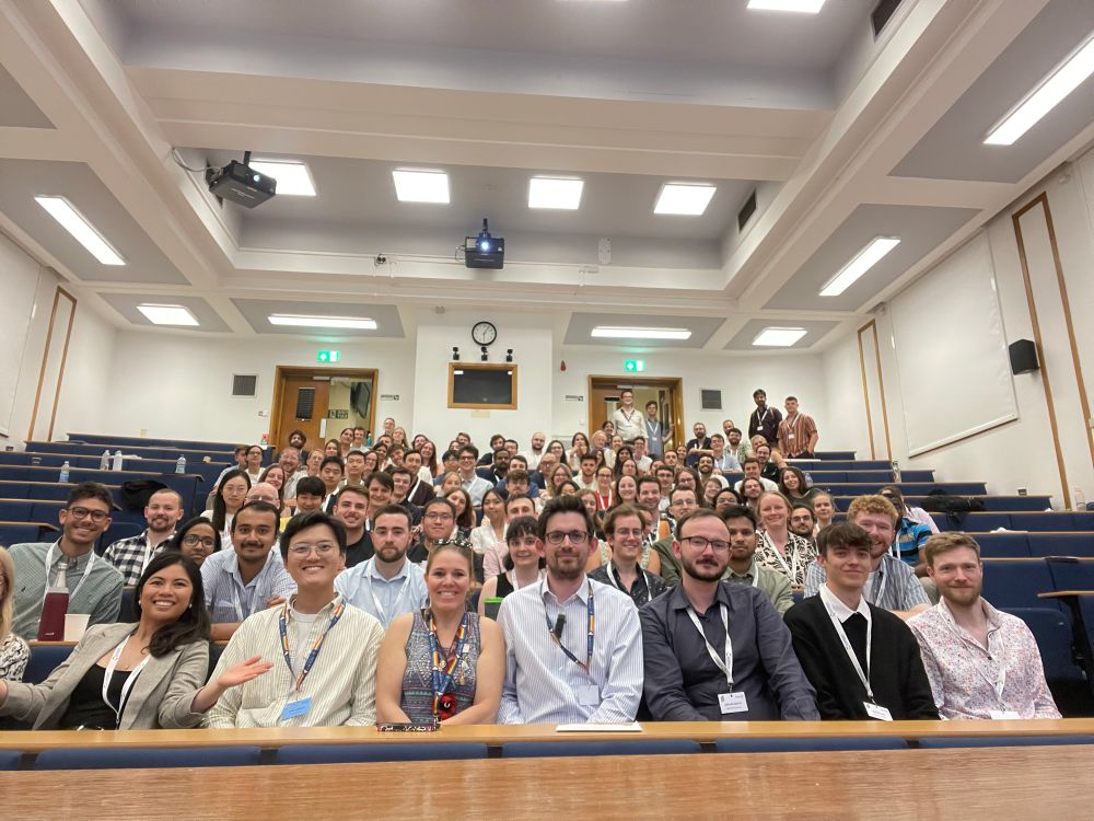 A group of people posing for a photo in a lecture theatre 