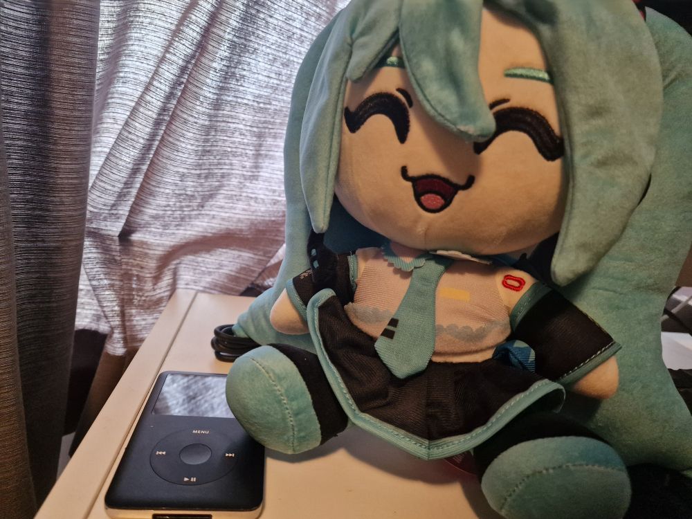 hatsune miku plush next to an ipod
