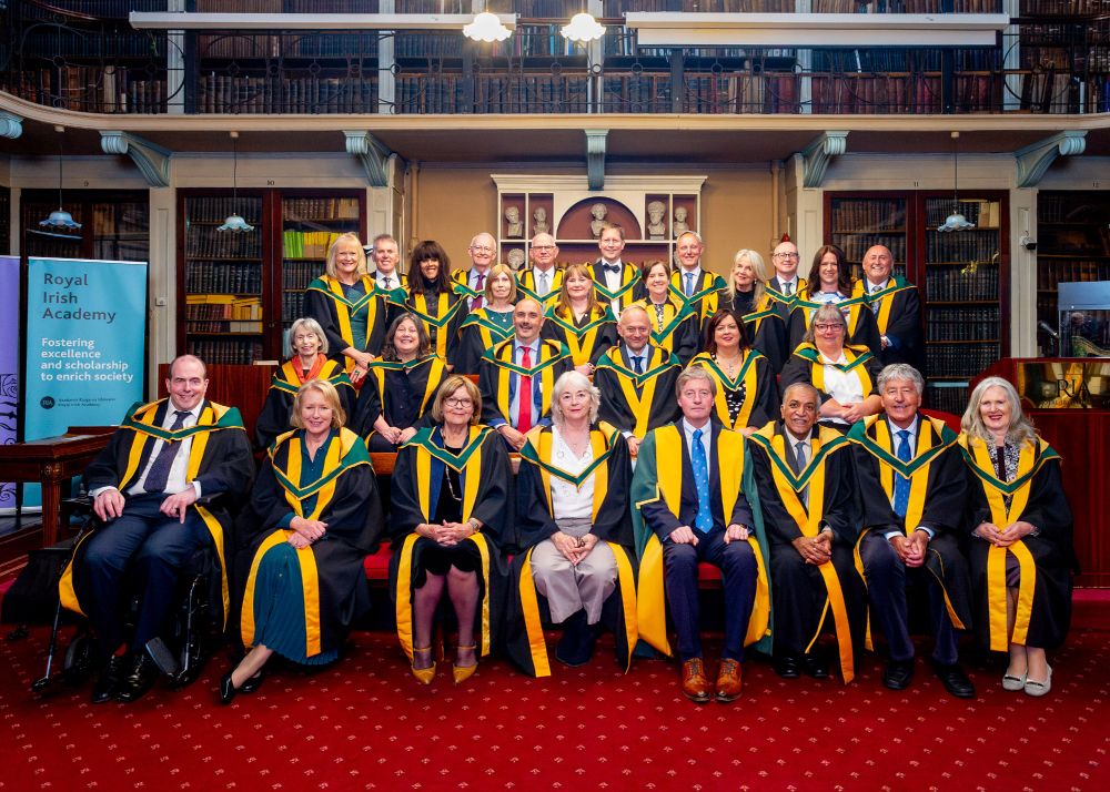 A group of individuals in graduation robes and caps, smiling and posing for a photo after their ceremony