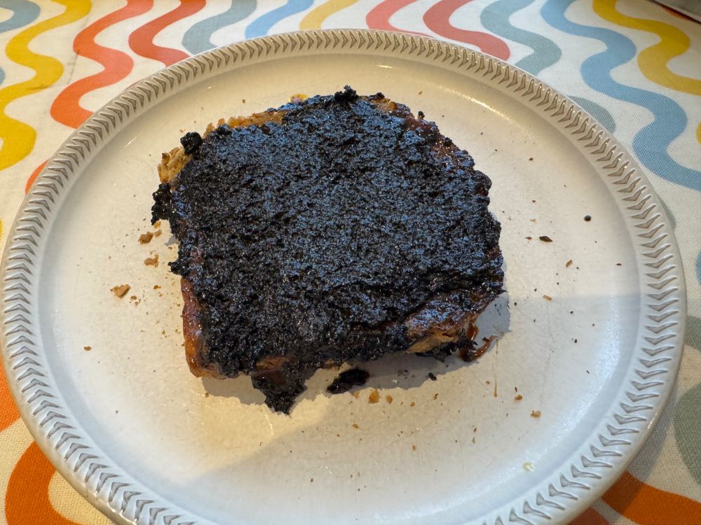 A piece of toast on a white plate covered by black tahini