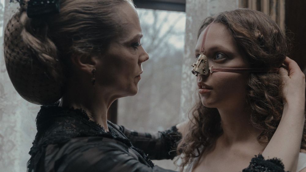 The Ugly Stepsister (film still)- a woman adjusts her frightened teenage daughter’s mechanical nose cast 