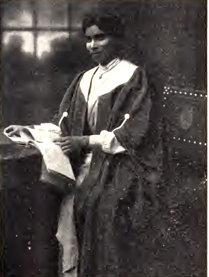 Black and white photograph of Dr Nallamma seated in robes handling a register.