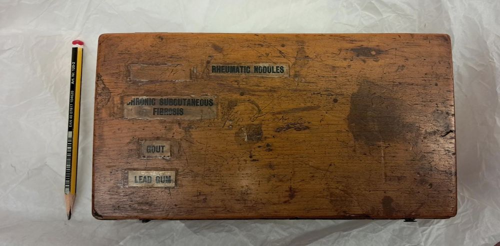 A small brown box with labels and a pencil lying beside it for scale.