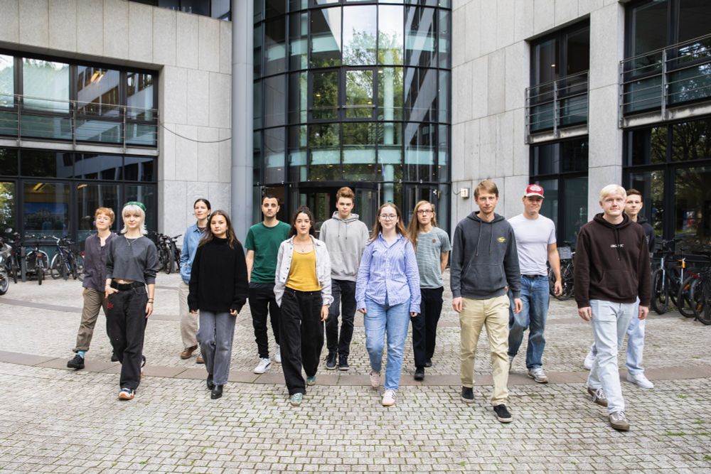 Insgesamt 13 Azubis gehen vor dem Eingang im Mittelweg 177 auf die Kamera zu.