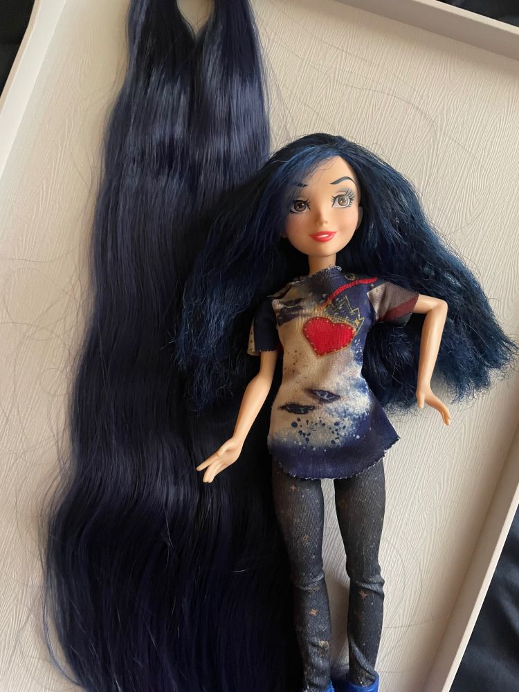 The doll with her original polypropylene hair, laid next to the new nylon in a long bunch