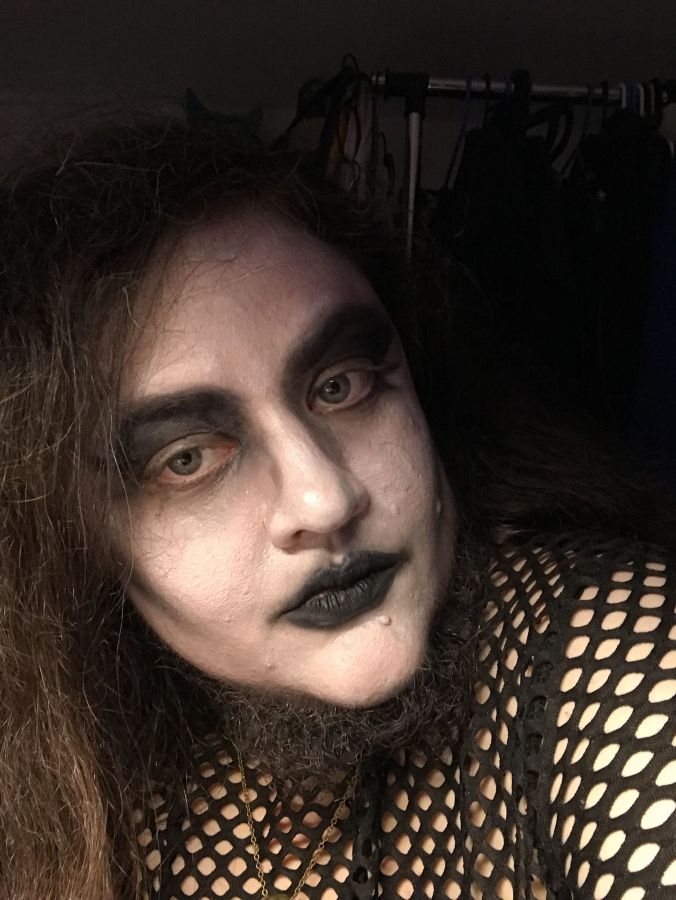 long haireed man in black and white makeup and a beard looks slightly to the side with black background