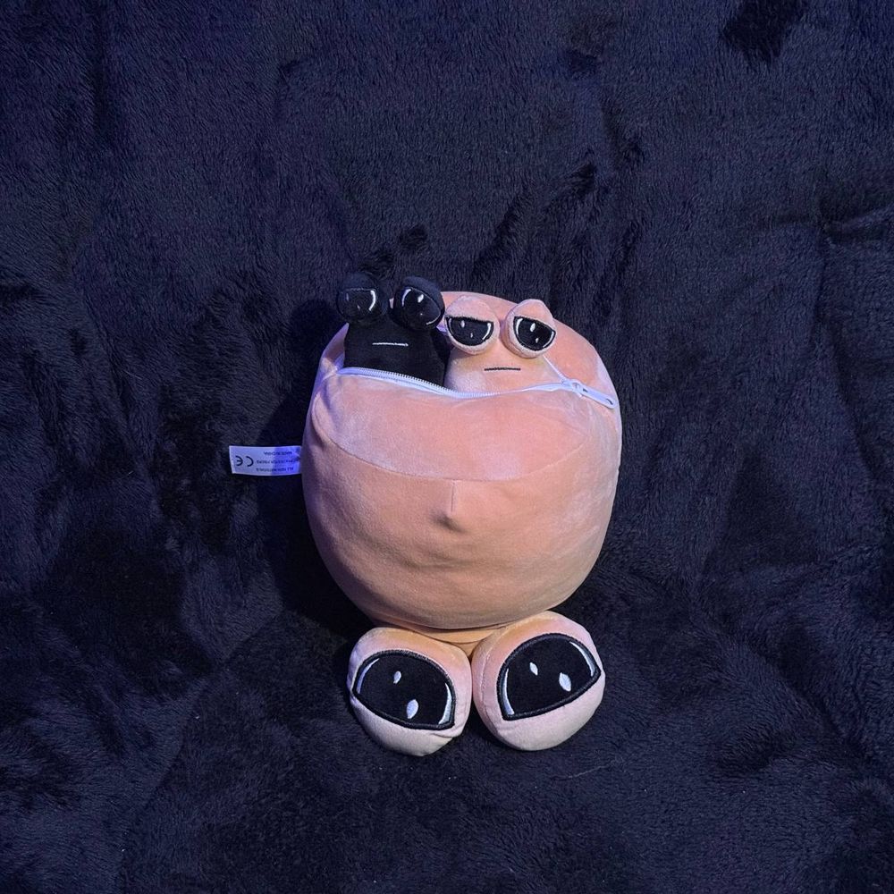 The same pou is now upside down with the zipper open. You can see two small pous poking out of the pouch.
One of the small pous has the same black coloring as the two colored pous from the previous posts, and the other is using the standard pou color.