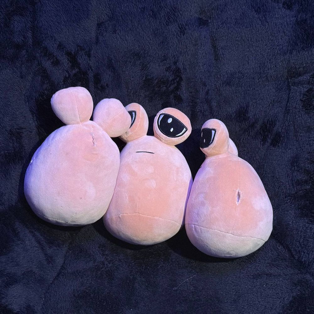 The same three plushies, but with two of them facing away from the camera.
One has visible stitches on its back, and the other has a ripped hole on the side.