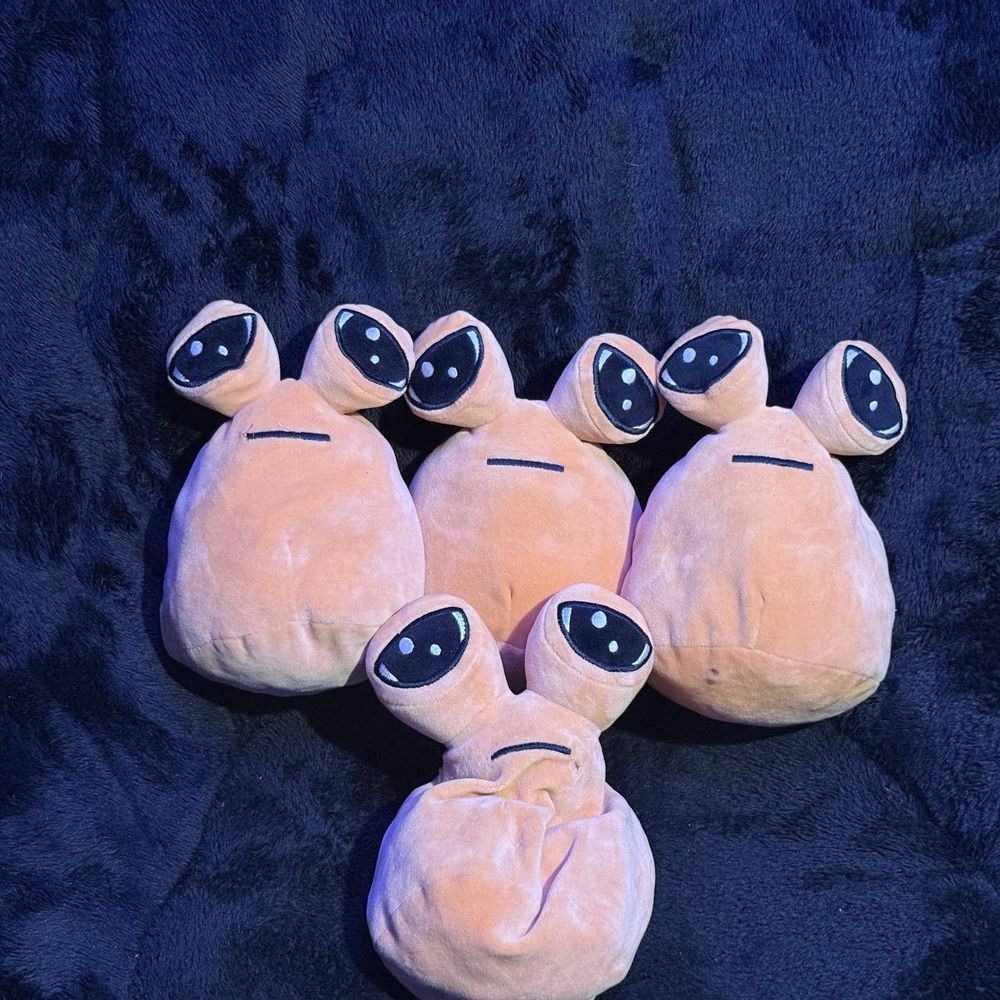 Four pou plushies on a dark background facing the camera.
Three of them are forming a row, and the final most deflated pou is below them at the center.