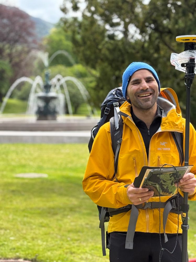 First day of field work! PhD student Hanif Kawousi starting his field work by sampliing a vegetation plot in an urban park. In this picture he is standing, smiling, with a tablet and weseing a yellow rainjacket and a blue hat. In the background, a water fountain… that’s urban ecology for you! 
