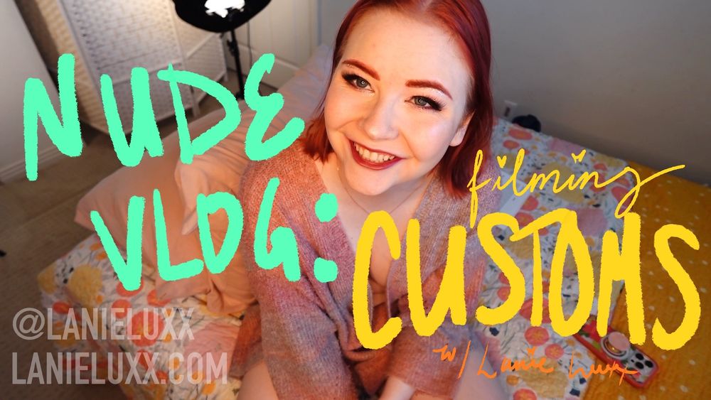lanie smiling on her bed, nude but wearing a cardigan. there's handwritten words across the image, "NUDE VLOG: filming CUSTOMS w/ Lanie Luxx"