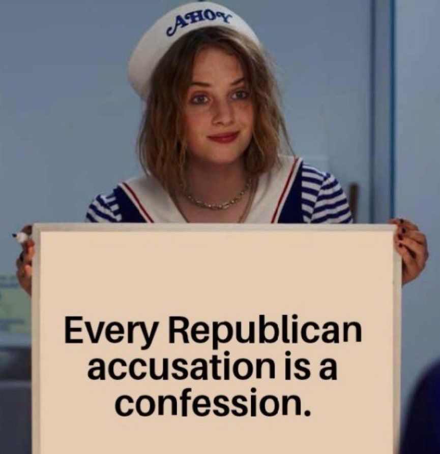 A girl in a sailor suit holding up a sign that says “every Republican accusation is a confession”