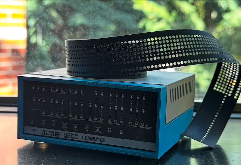 A model of an Altair 8800, with a roll of paper tape sitting on top. The paper tape stores a 4K version of BASIC.