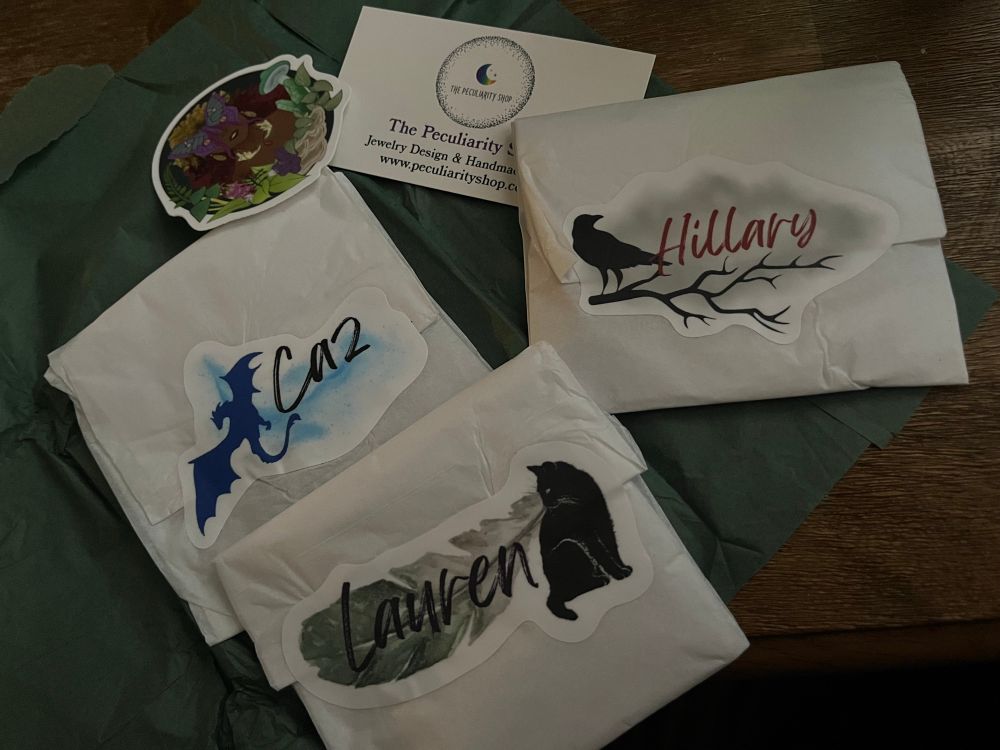 The packaging creating anticipation- 3 small white tissue paper wrapped jewelry with stickers of each maker’s name. Also the Peculiarity Shop business card and a gorgeous fae sticker. 