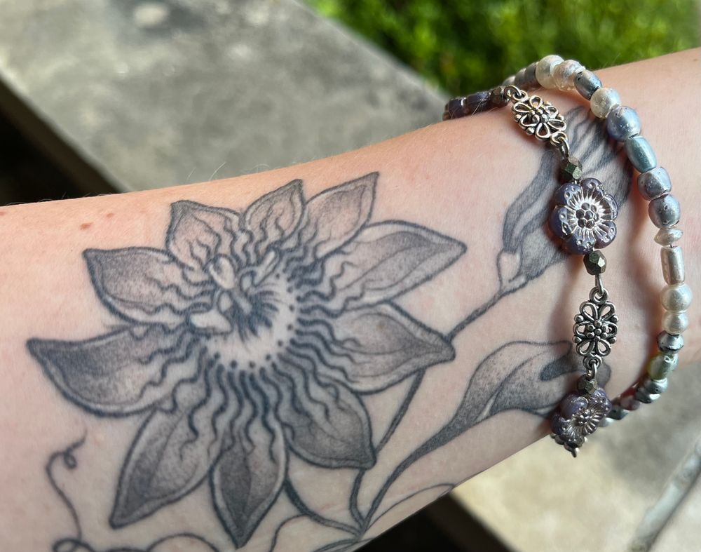 White woman’s forearm with a passionflower tattoo wearing the passionflower bracelet