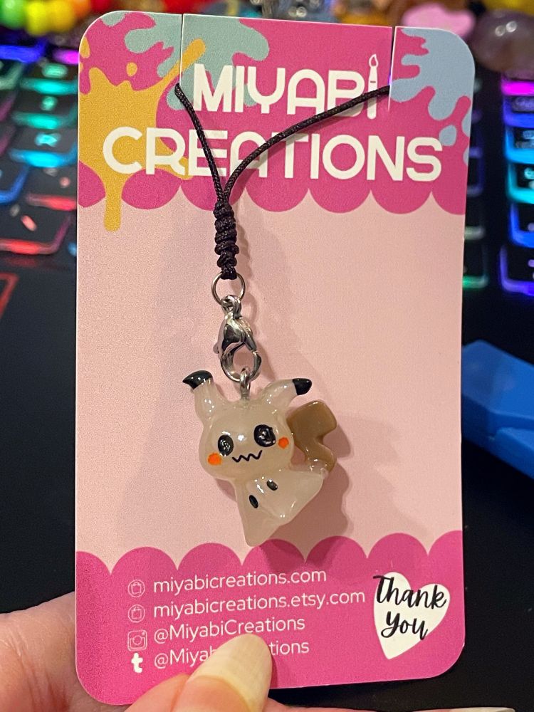 A lil phone charm of the pokemon Mimikyu by Miyabi Creations