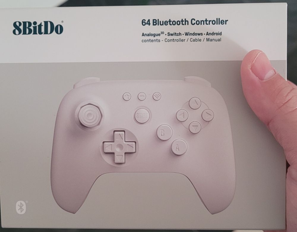 Caixa do novo controle da 8bitDo para jogos de Nintendo 64
Caixa cinza com uma faixa branca no topo e a foto do controle ao centro. 
