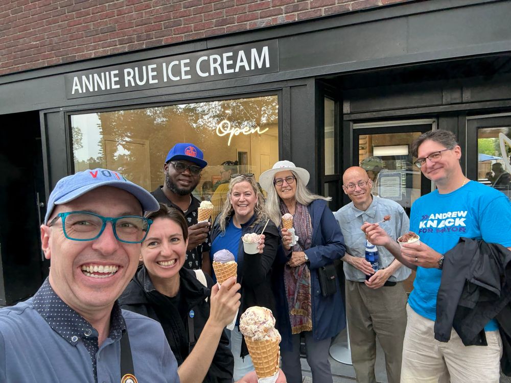 A group of people standing in front of the Annie Rue Ice Cream shop holding ice cream.