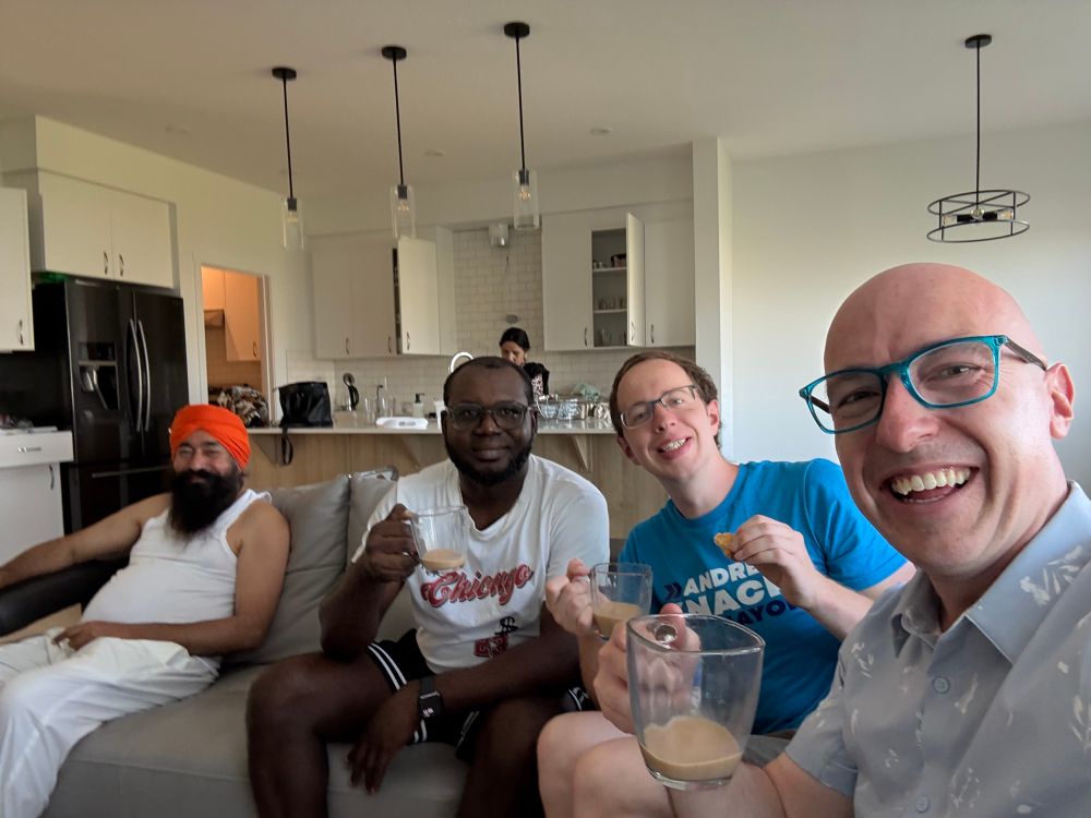 A group of people sitting on a couch holding cups of tea.