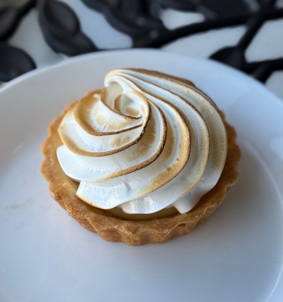 A lemon meringue tart on a white plate.