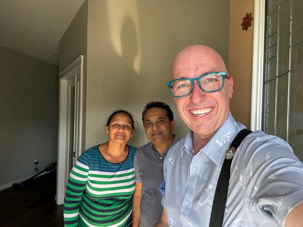 Andrew and two others smiling at the camera while just inside the front of the home.