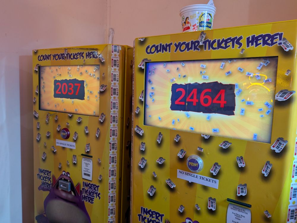 A photo of two yellow machines intended to count the number of tickets you have collected. The left reads 2037, and the right reads 2464.