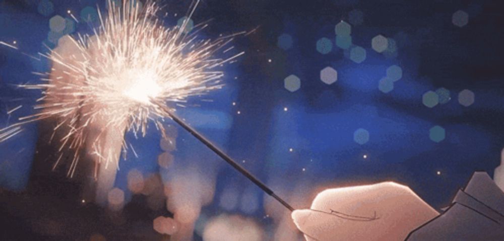 a person is holding a sparkler in their hand in front of a blurry background