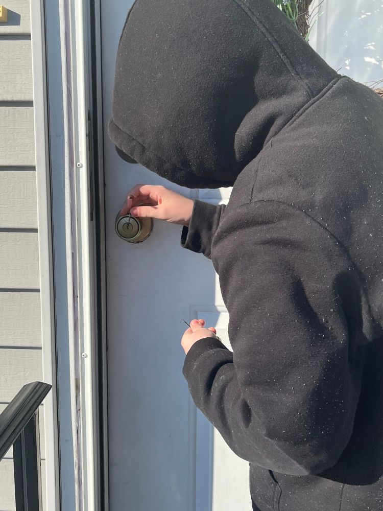 Picture of a child at a door attempting to use a lock pick 