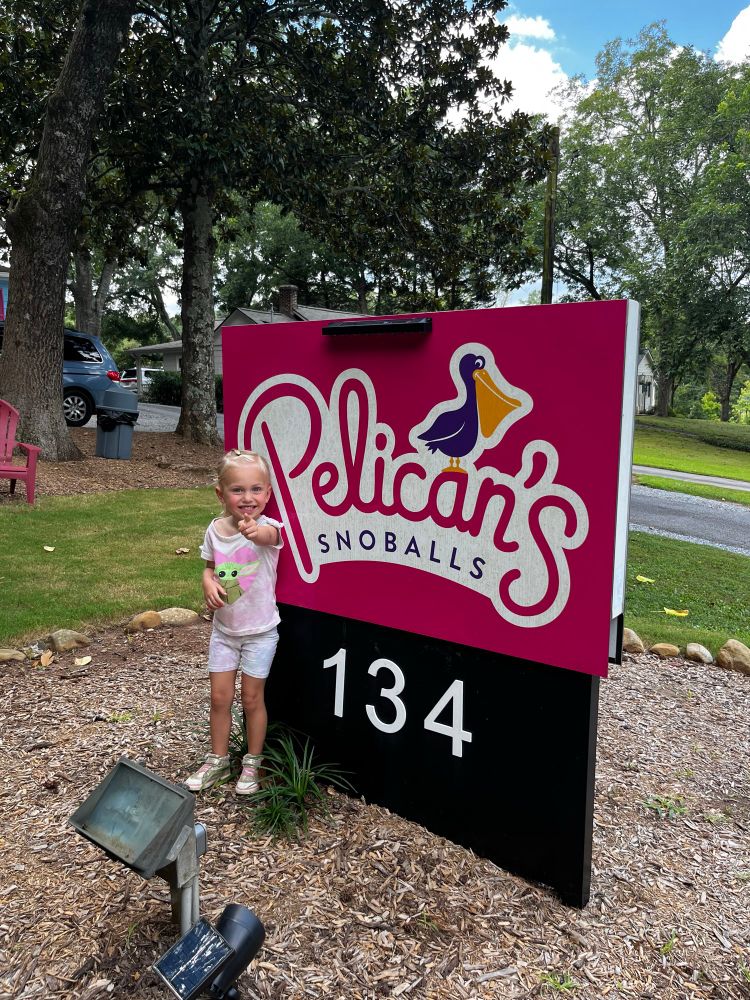Kid standing next to a Pelican’s sign